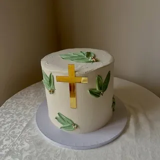 The white buttercream cake with a gold cross and hand painted green leaves this comment was left on