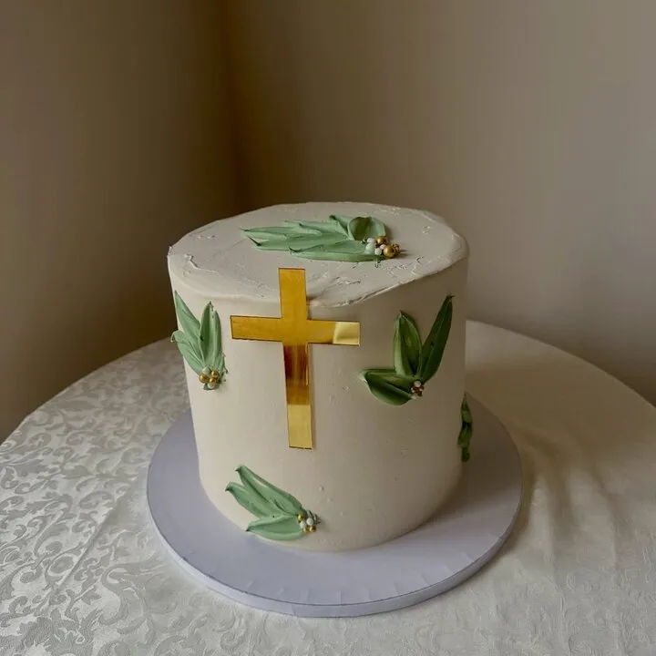 The white buttercream cake with a gold cross and hand painted green leaves this comment was left on