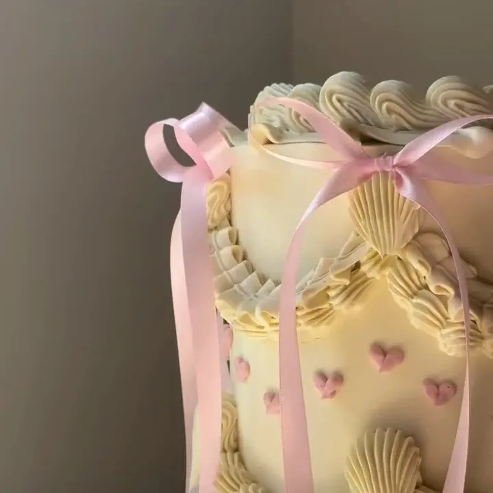 The cream buttercream cake with piped shells and pink satin bows this comment was left on