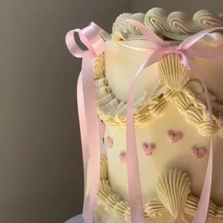 The cream buttercream cake with piped shells and pink satin bows this comment was left on