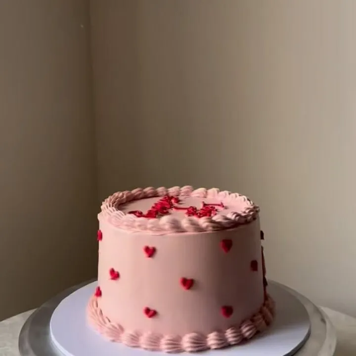 The pink buttercream cake covered in small red piped hearts this comment was left on