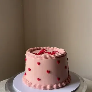 The pink buttercream cake covered in small red piped hearts this comment was left on